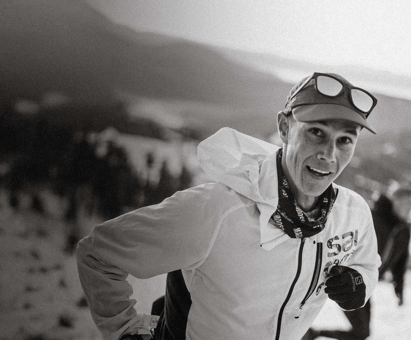 Person running in a snowy landscape wearing a white jacket and black pants.